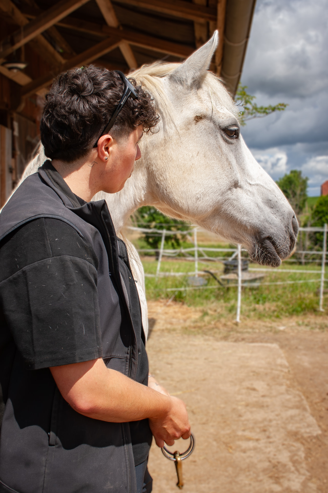 Noa, ergonome équin, aux côtés d'un cheval gris